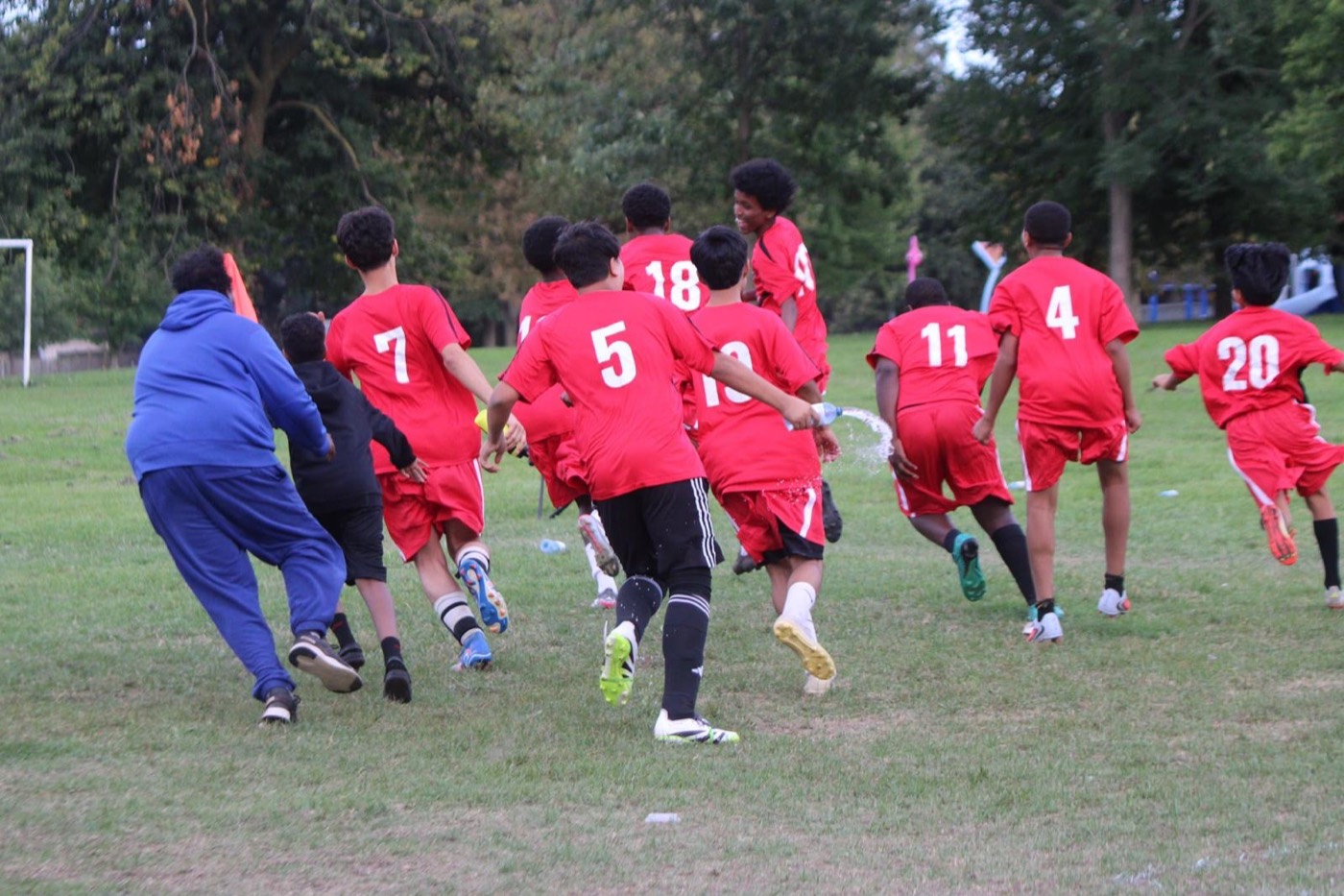 Young players and their coach run to celebrate together